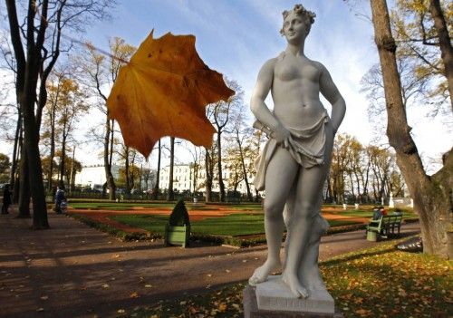 Una hoja amarilla se cae al lado de una estatua en el Jardín de Verano en el centro de San Petersburgo