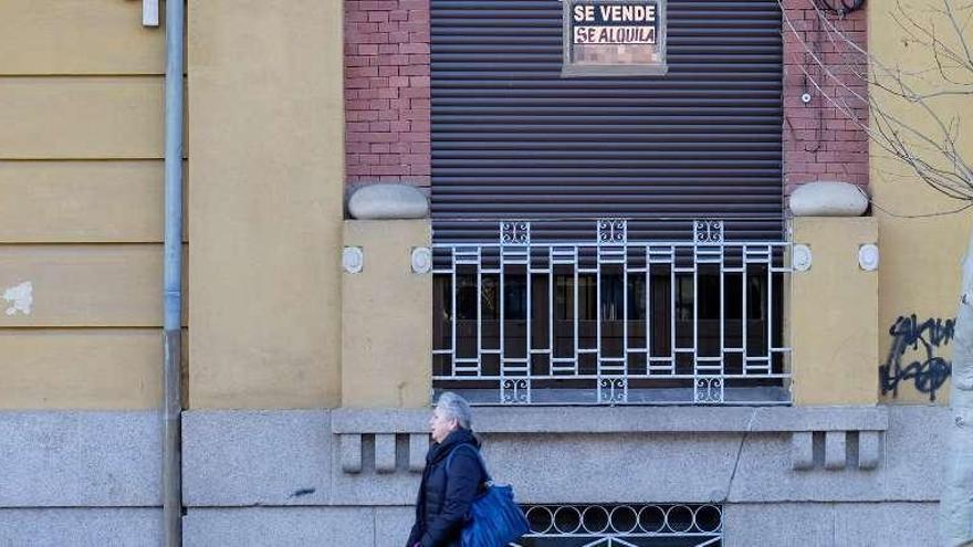 Una mujer pasa frente a una vivienda en alquiler.