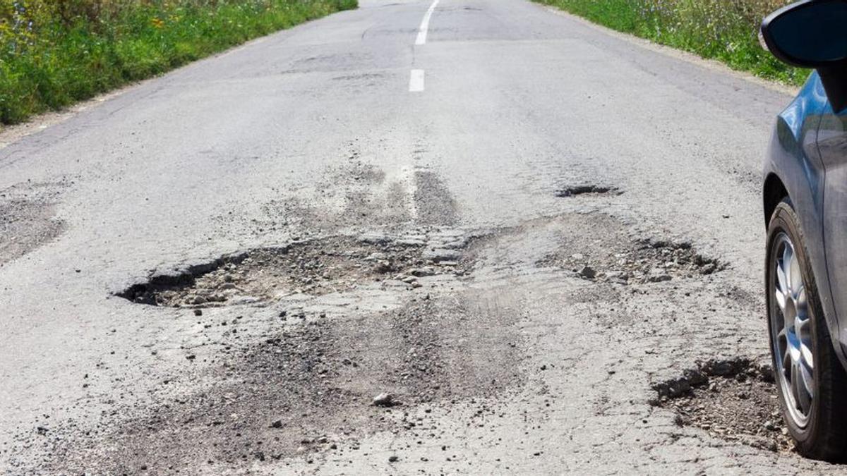 Imagen de baches y grietas en el pavimento de una carretera.