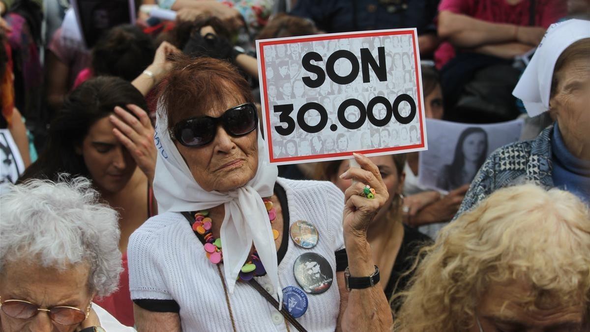 Una mujer sostiene un cartel en referencia a los 30.000 desaparecidos mientras escucha el veredicto por los crímenes cometidos en la ESMA, en Buenos Aires, el 29 de noviembre.