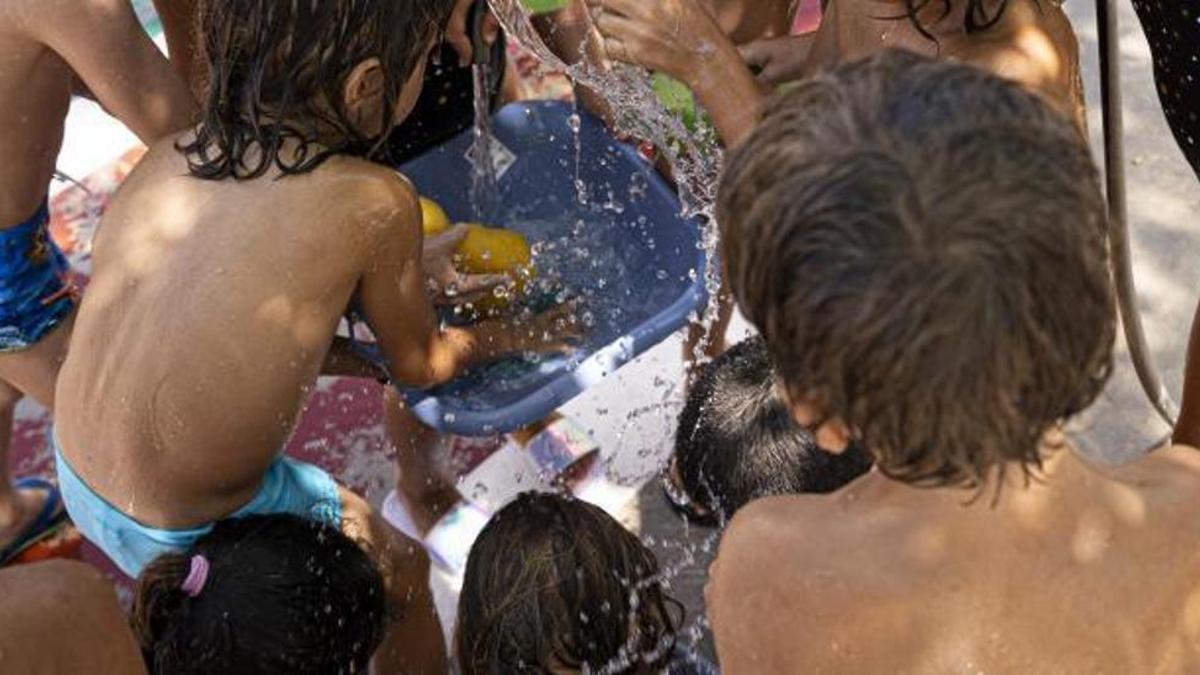 Los niños disfrutan mojándose durante la hora del patio mientras se tiran agua entre ellos.