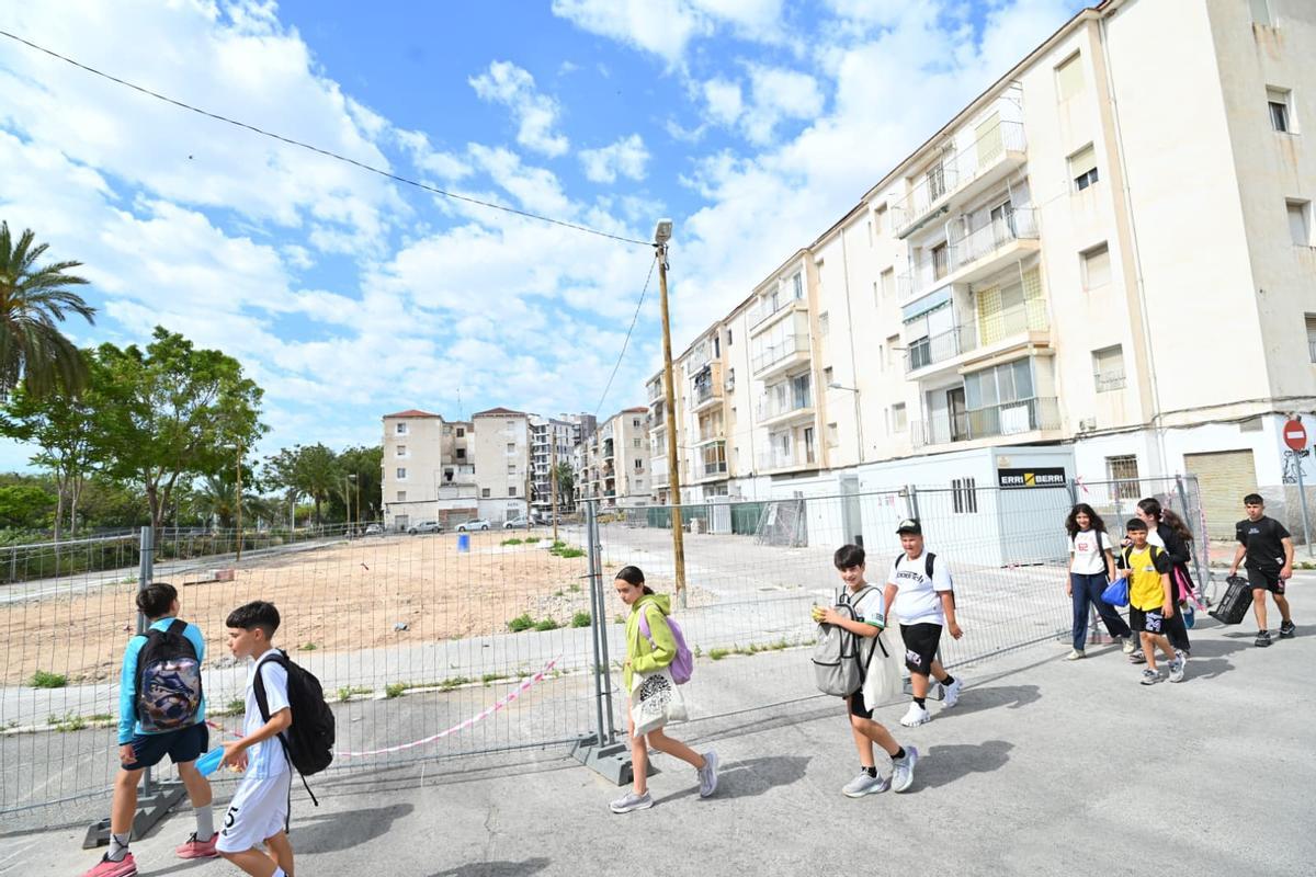 Escolares pasan junto al vallado que ha instalado el Ayuntamiento sobre los solares vacíos