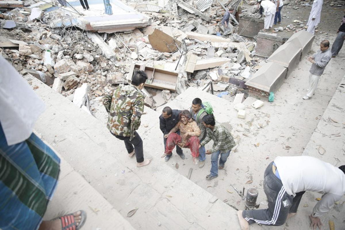 Un grupo de personas consigue sacar a una mujer de los escombros de un edificio de Nepal.