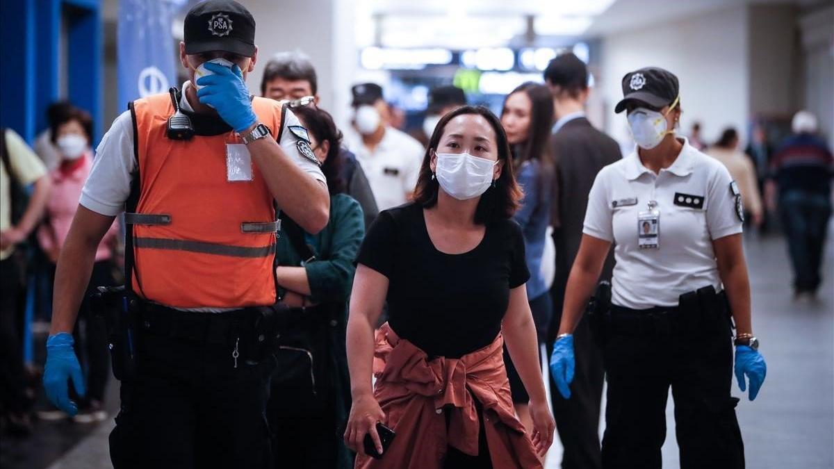 Policías argentinos separan a turistas europeos a su llegada al aeropuerto Jorge Newbery de Buenos Aires, en prevención por la pandemia de coronavirus.