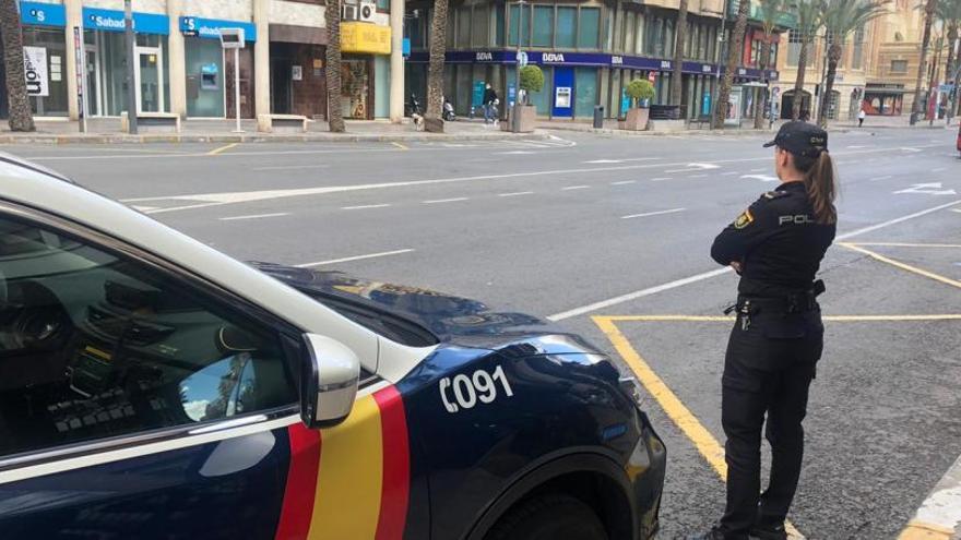 Una policía nacional frente a dos sucursales bancarias en la avenida Alfonso el Sabio de Alicante.