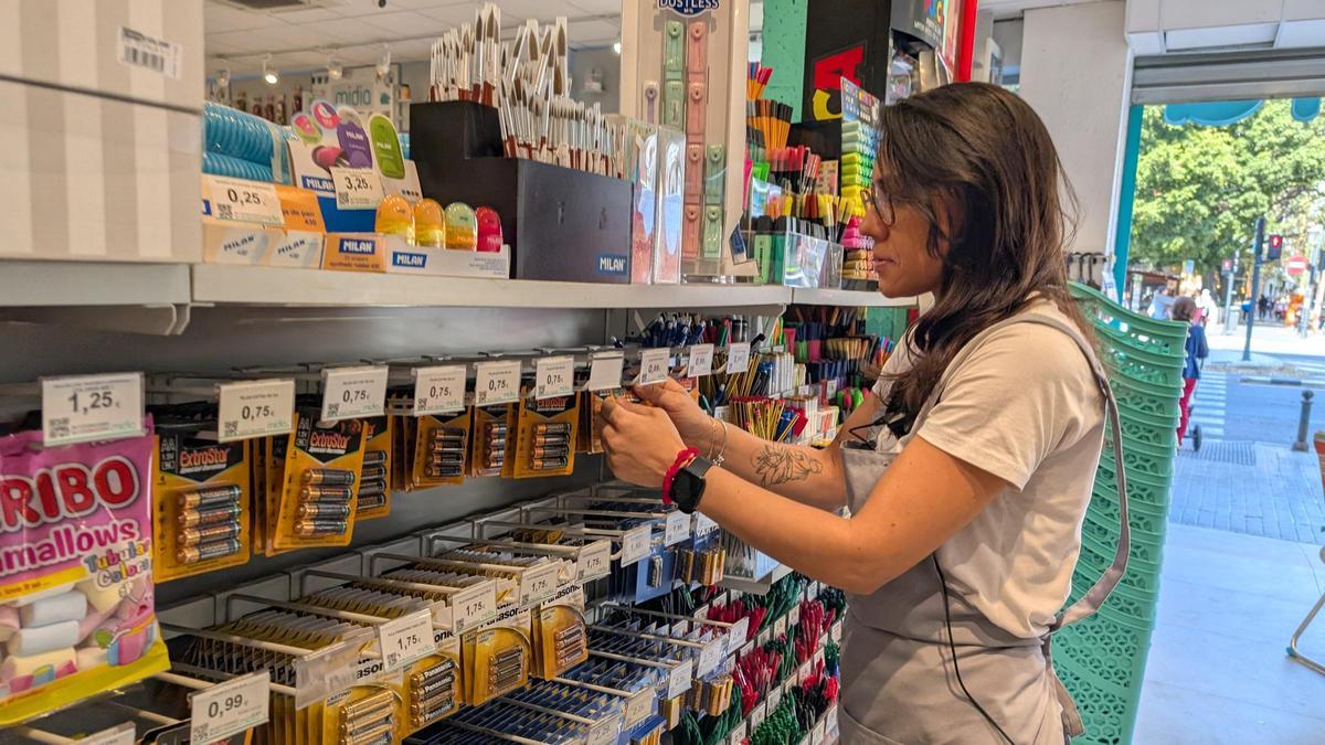 Una trabajadora de una tienda reponiendo las pilas.