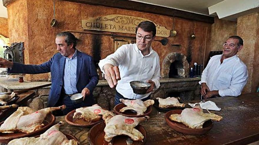 Alfonso Fernández Mañueco coloca lechazo en el horno durante su visita a la localidad de Roa de Duero.