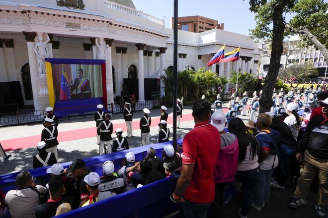 Government supporters and military guard listen to Venezuelan President Nicolas Maduro speak after his swearing-in ceremony for a third term as they watch a live video of him on a screen outside the National Assembly in Caracas, Venezuela, Friday, Jan. 10, 2025. (AP Photo/Matias Delacroix)