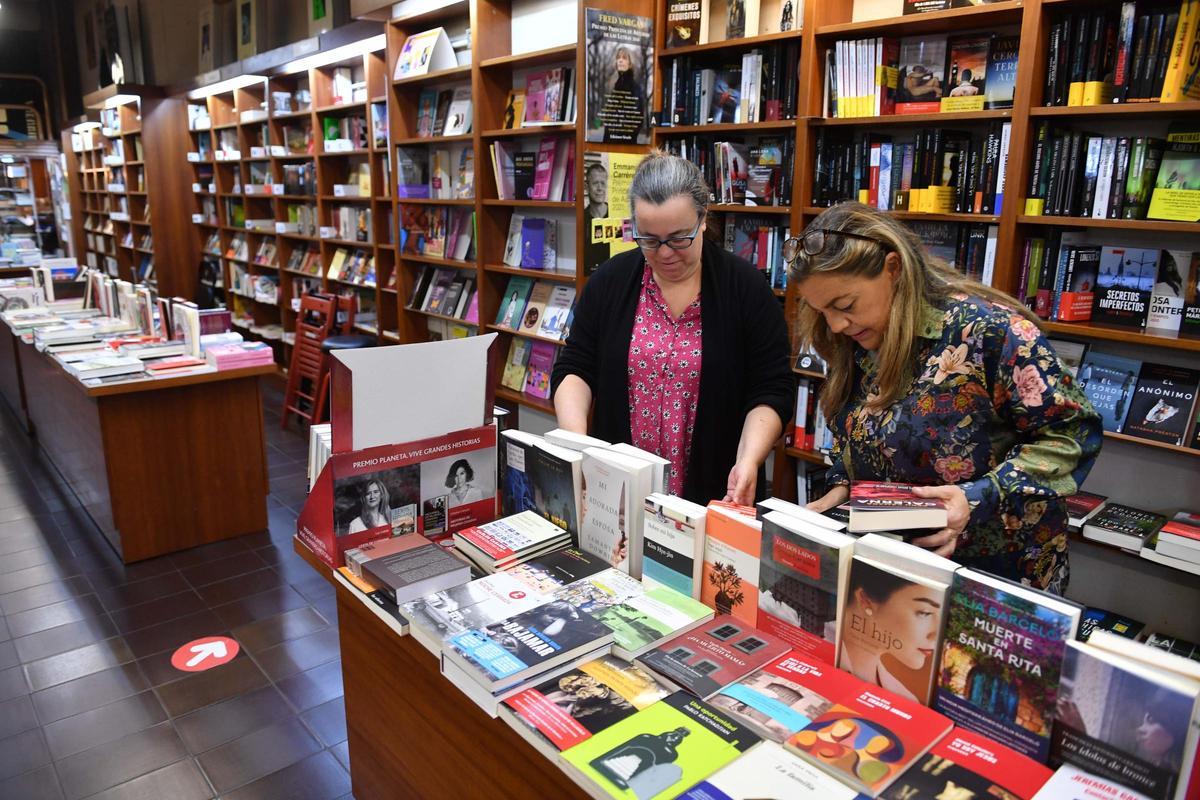 Dos mujeres ojean libros en una librería de A Coruña.