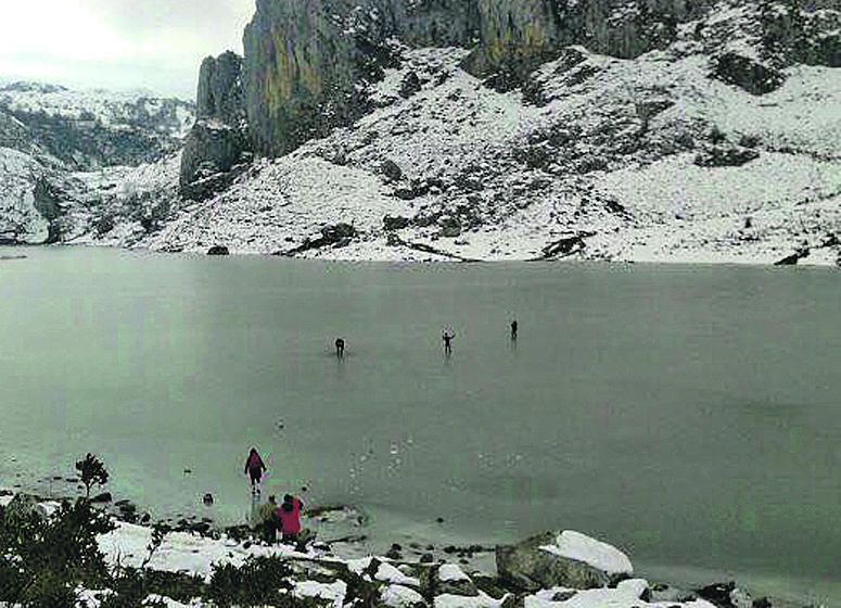 Turistas caminando sobre el lago Ercina