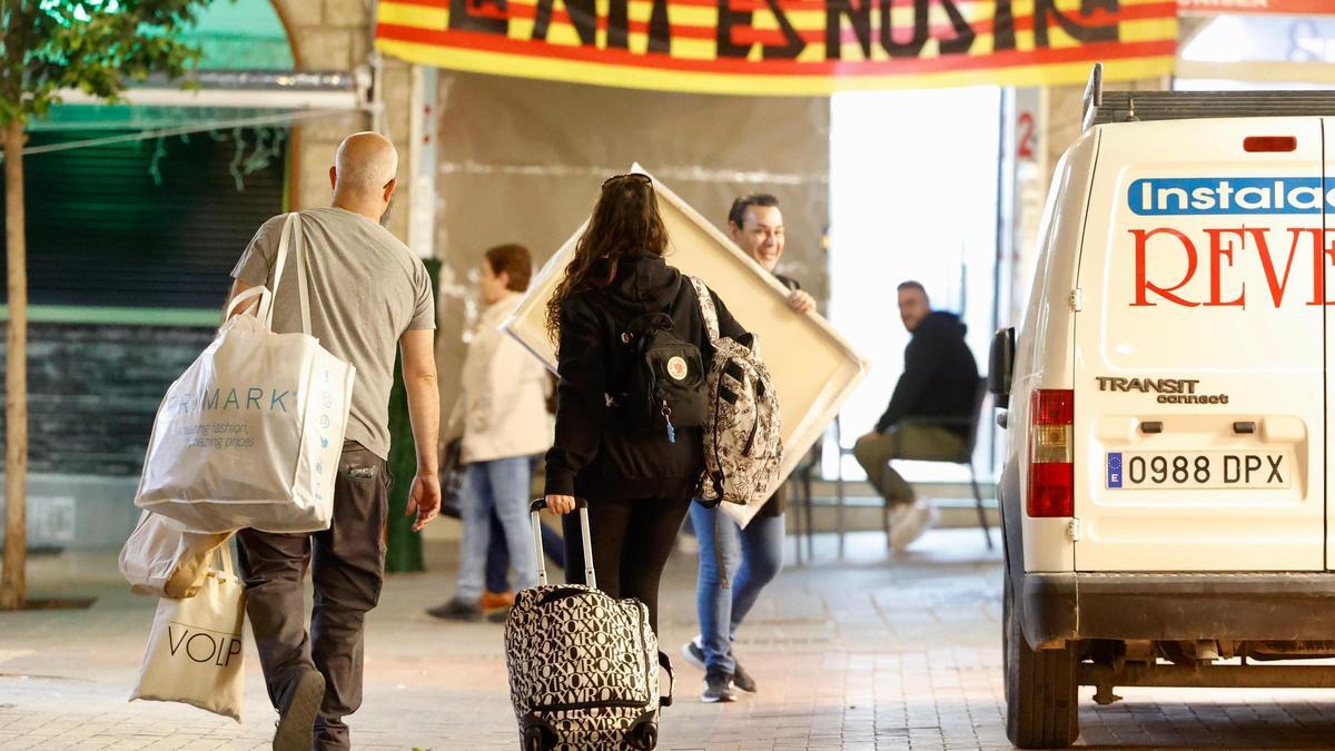 Dos personas con maletas y bolsas en una de las calles del centro de Benidorm este jueves.