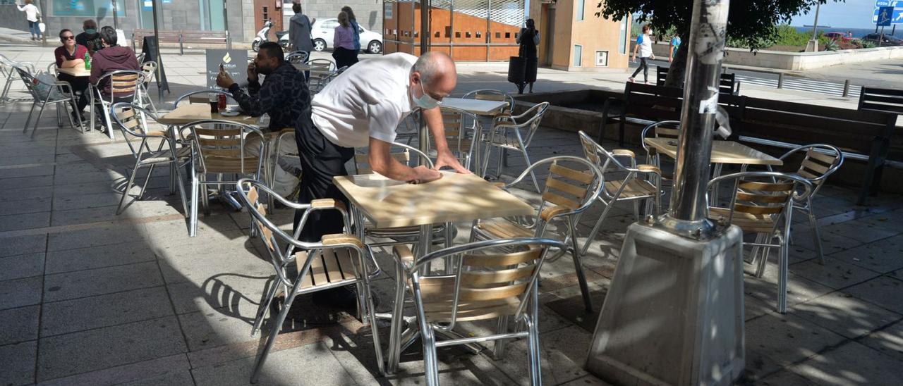 Un camarero limpia una mesa en una terraza de Las Palmas de Gran Canaria. | | JOSÉ CARLOS GUERRA