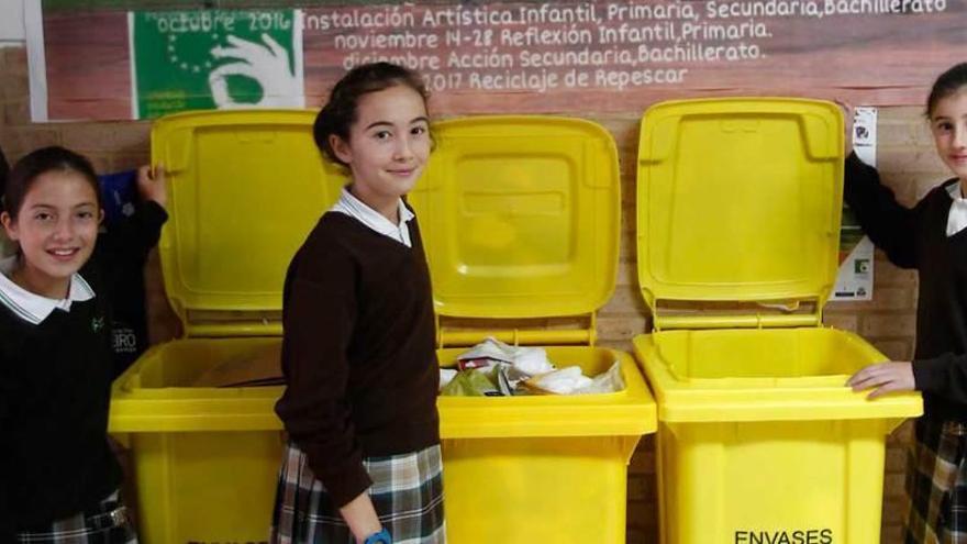 Arriba, por la izquierda, Sofía Santos, Anna Montoto y Lucía Álvarez, en el punto de reciclado del colegio. A la izquierda, Mauro García dobla una bolsa de plástico.