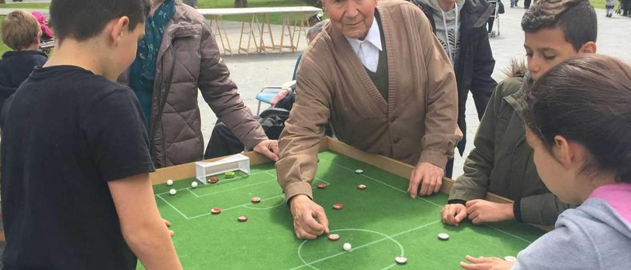 Niños y mayores juegan a las chapas en una de las jornadas intergeneracionales.