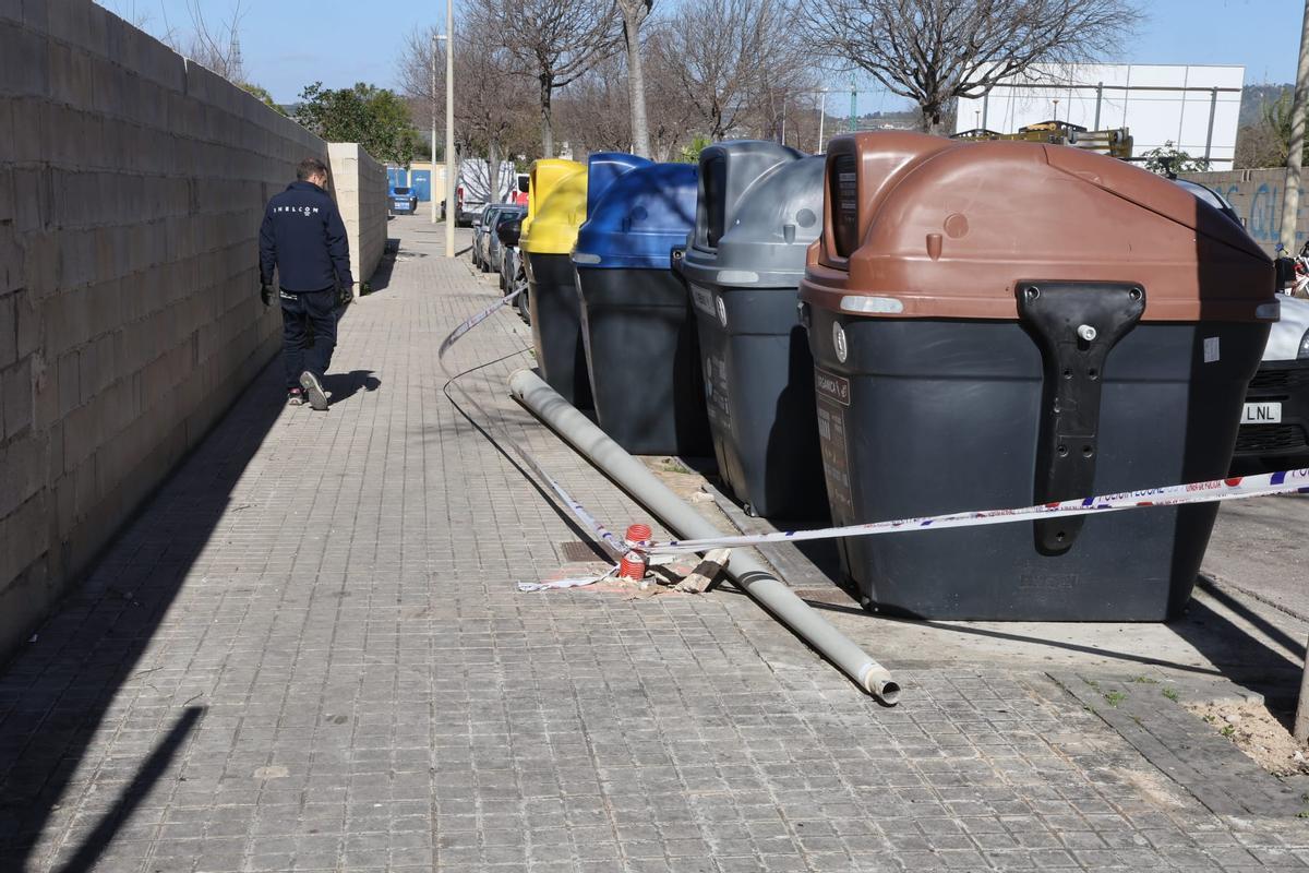 Un hombre pasa por delante de unos contenedores donde cayó un poste, en un municipio de la Costera.