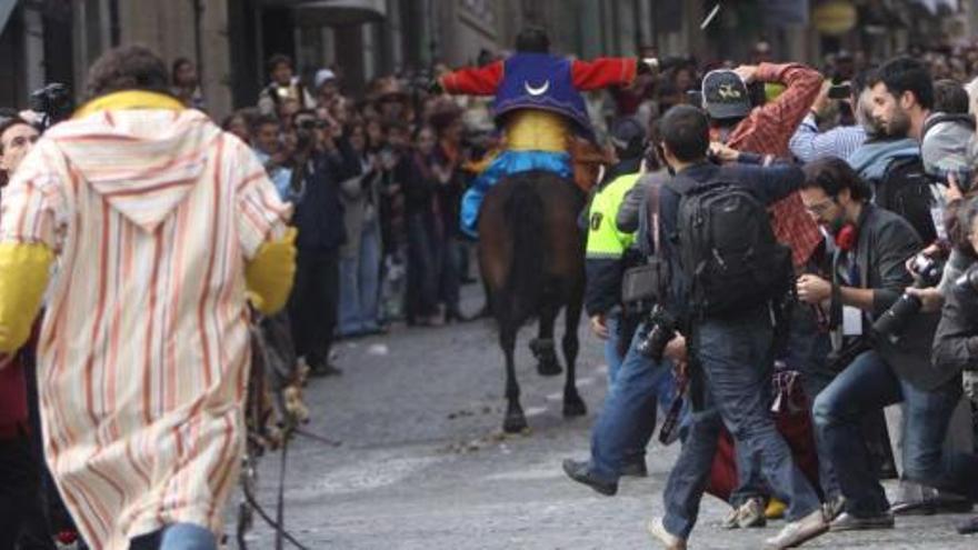 Numerosos espectadores y fotógrafos se afanan por presenciar la carrera a caballo del emisario moro en la Estafeta, que va en busca de los suyos para iniciar la Embajada.