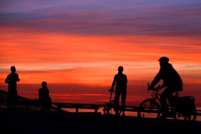 Varios ciudadanos observan el amanecer mientras hacen ejercicio o salen a dar un paseo en el Paseo Marítimo de Barcelona,