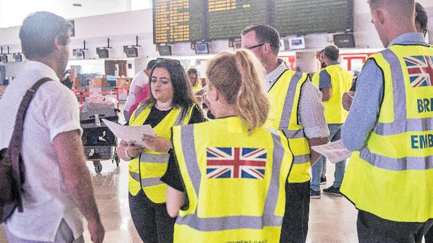 Un pasajero recolocado ayer en uno de los vuelos que salían del aeropuerto de Lanzarote habla con los funcionarios británicos desplazados.