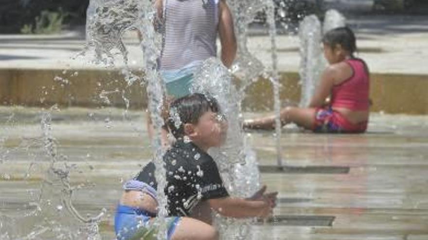 Un grupo de niños se refresca bajo los chorros de agua existentes en el Paseo de la Estación.