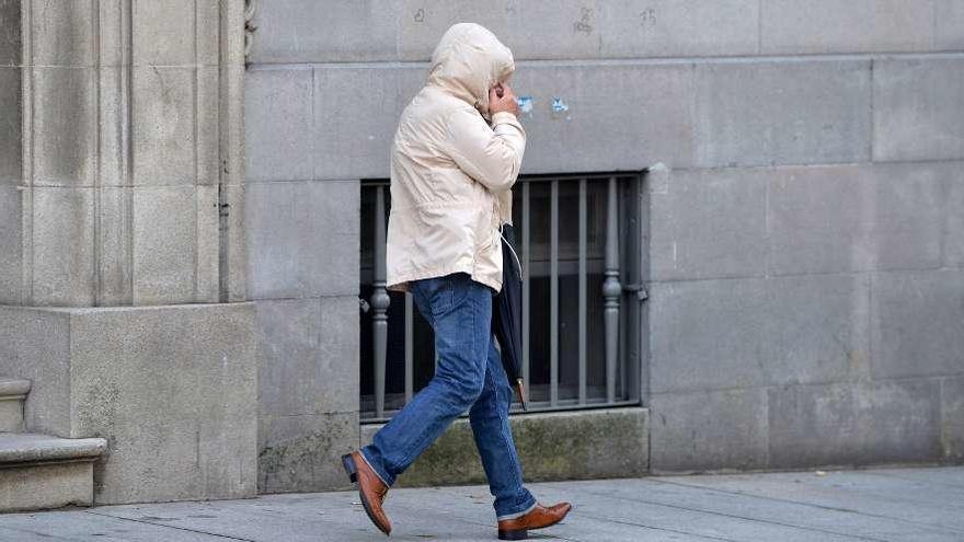 El acusado abandona el edificio de la Audiencia de Pontevedra cubriéndose el rostro. // G. Santos