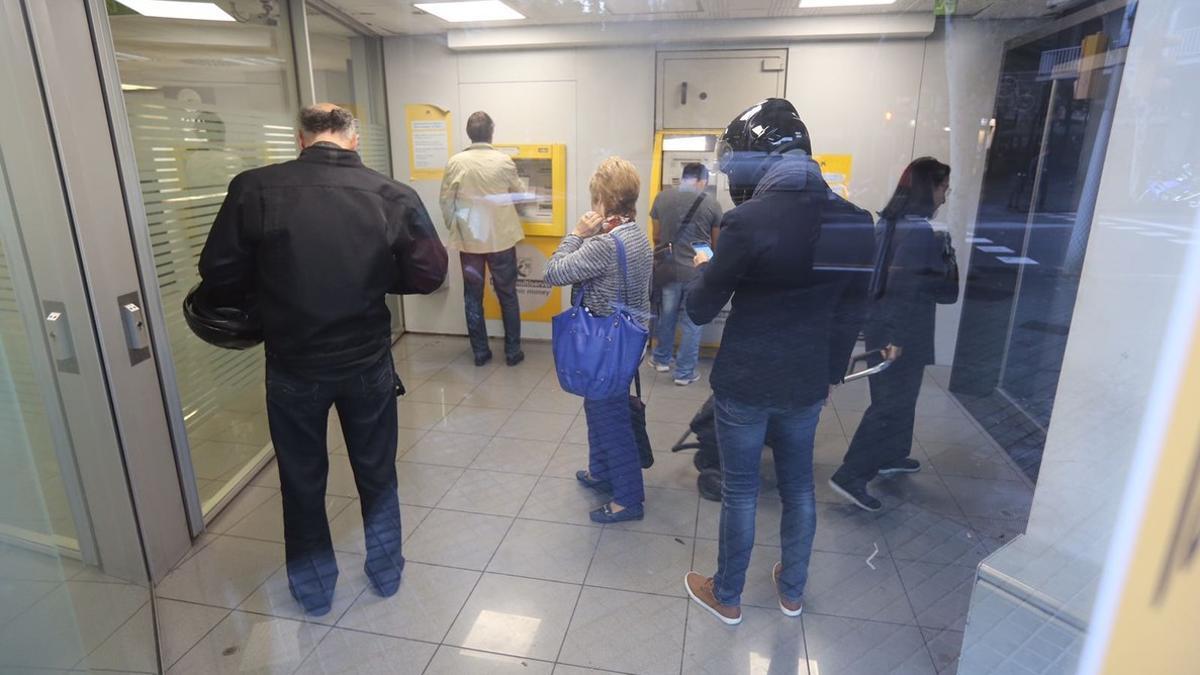 Pequeña cola en una sucursal de CaixaBank en Barcelona, este viernes a primera hora.