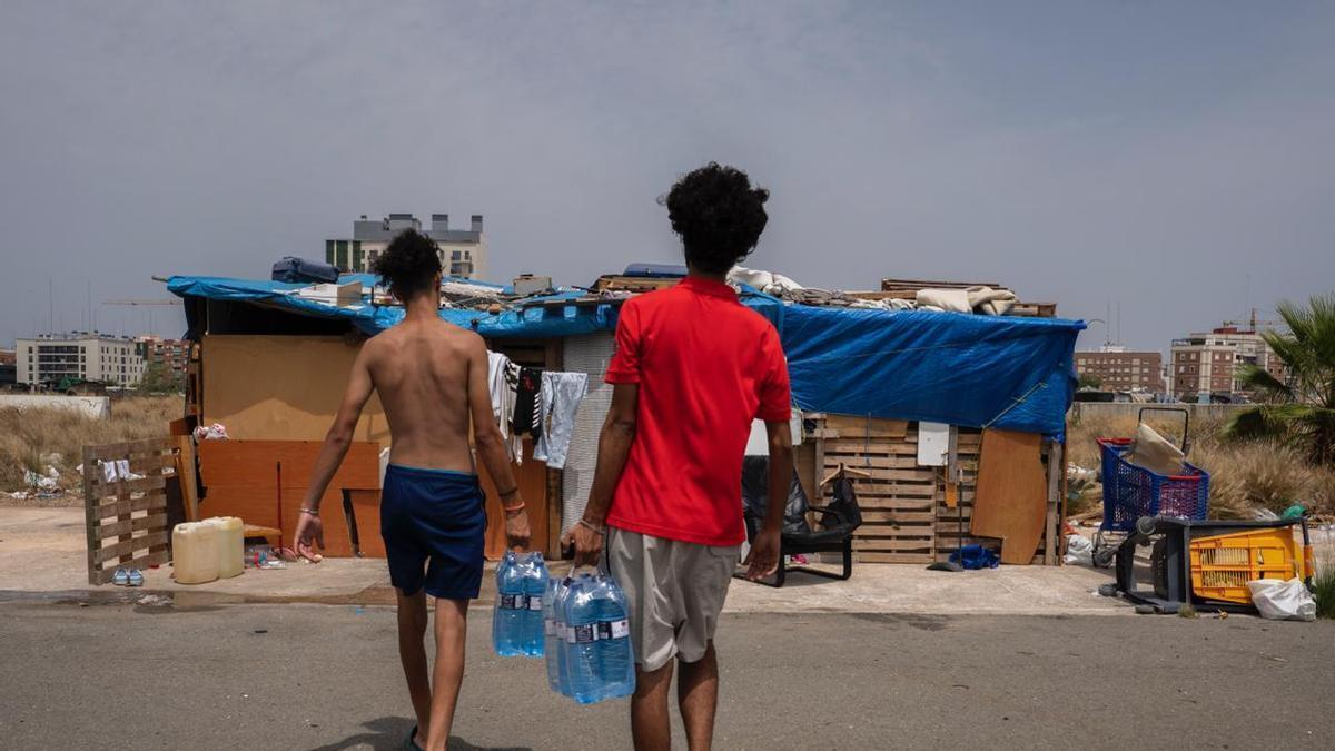 Dos jóvenes recogen el agua que reparte València és refugi.