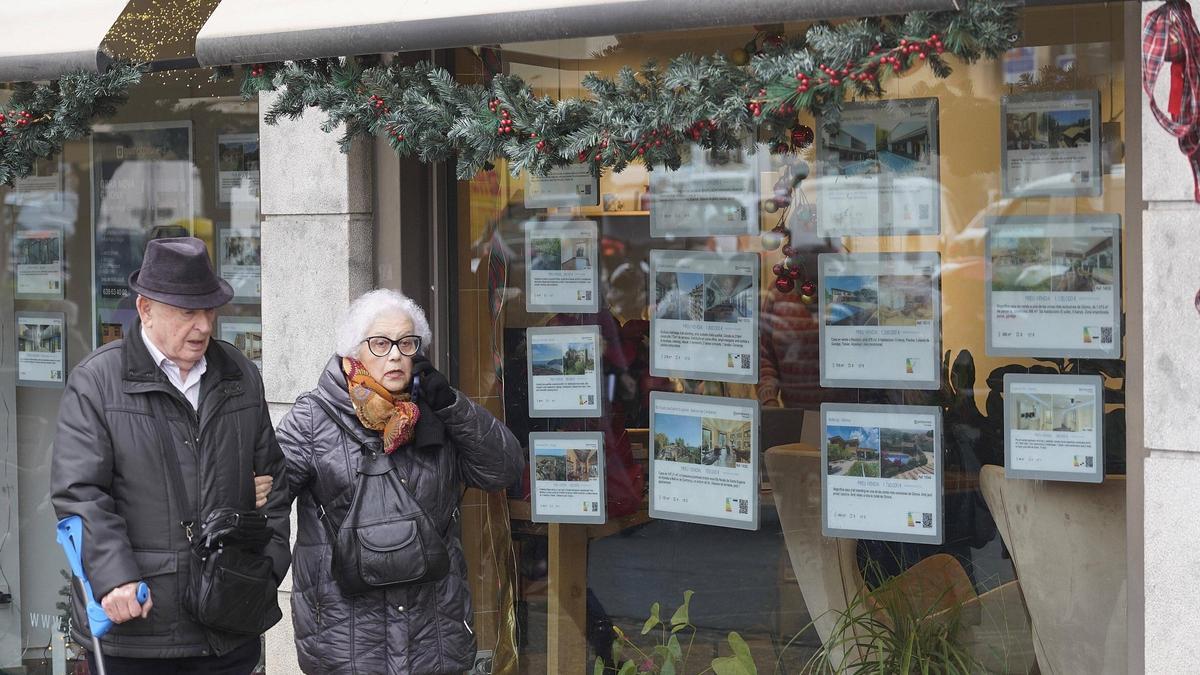 Dues persones davant de l'aparador d'una immobiliària a Girona.