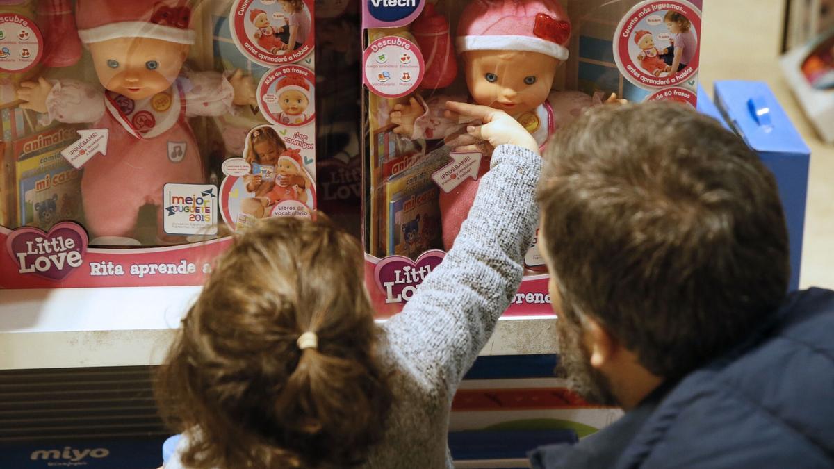 Una niña, con una muñeca en una tienda de juguetes