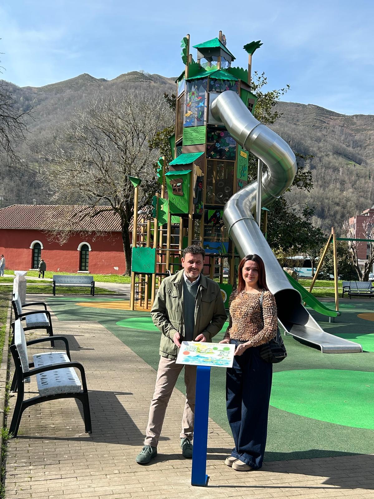 El alcalde de Laviana, Julio García, y la artista local Beatriz Barbón, con los carteles que fomentan el reciclaje en los parques infantiles