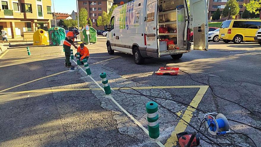 Operarios de Emulsa, colocando bolardos en un entorno escolar.