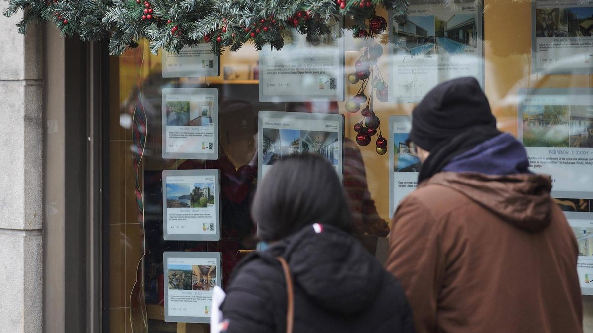Dues persones davant l'aparador d'una immobiliària a Girona.
