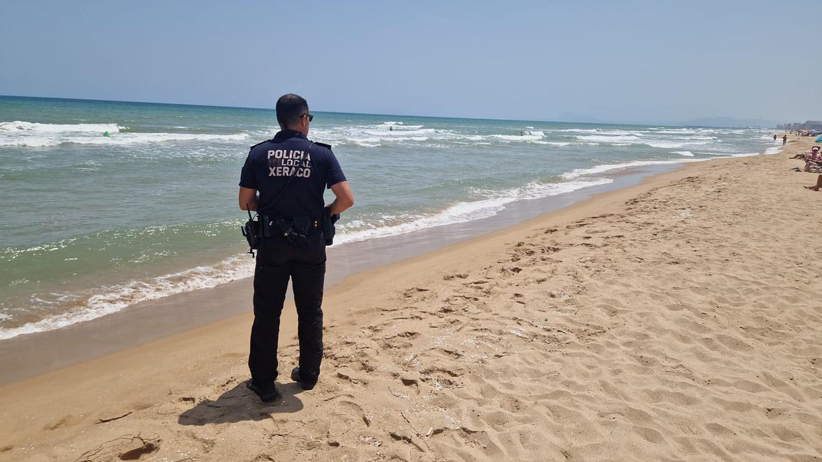 Un agente de la Policía Local de Xeraco inspecciona la zona de la playa.