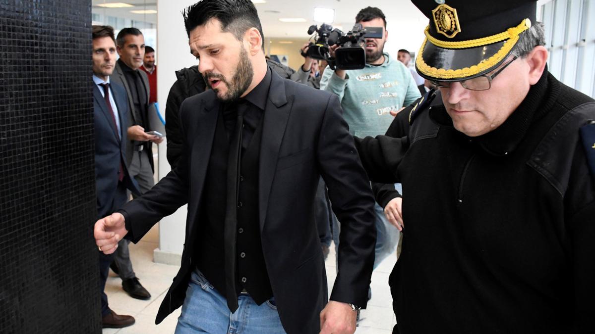 Matias Messi is escorted by a police officer outside the Criminal Justice Center in Rosario