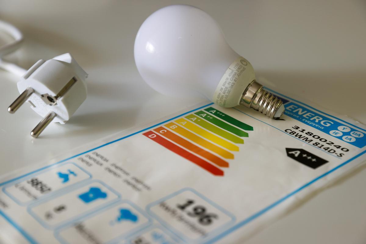 Una bombilla, un enchufe y un cuadro de consumo energético.