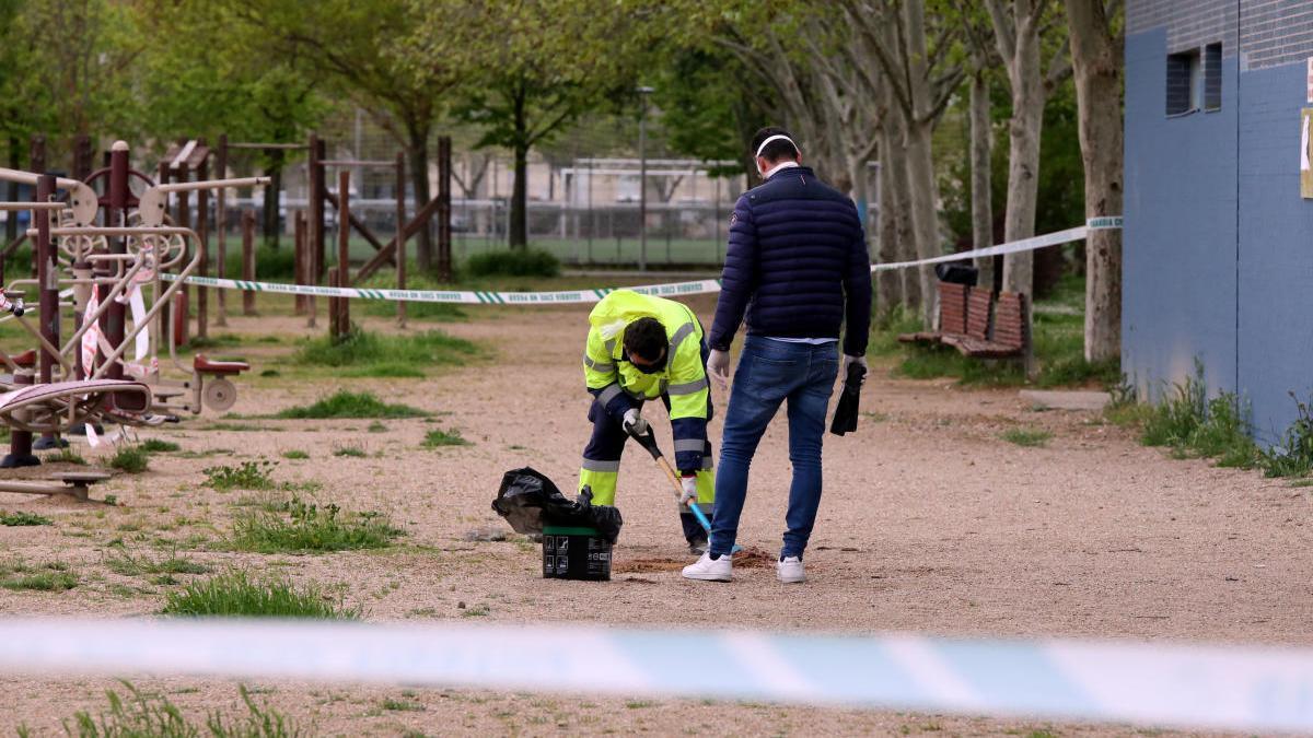 Dos operarios limpian la zona donde se ha hallado el cadáver de un joven de 18 años en Laguna de Duero, Valladolid.