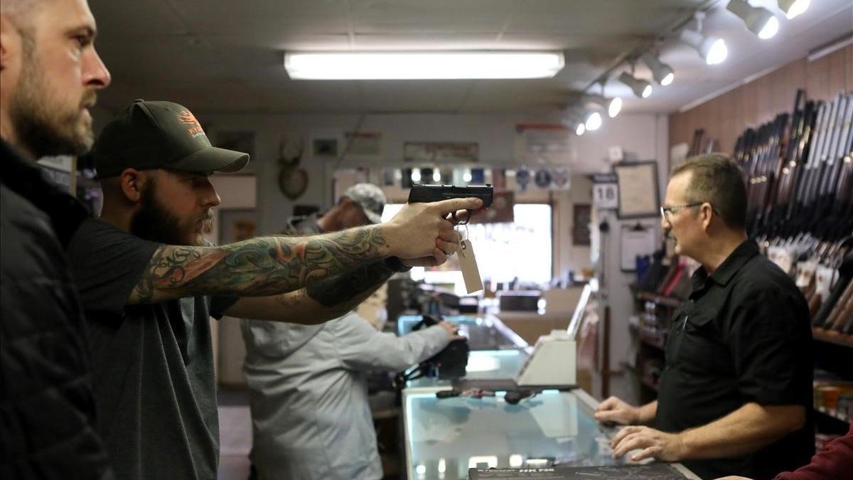 Un hombre sostiene una pistola en una tienda de armas en Cheyenne, Wyoming, ante el temor al caos por la propagación del coronavirus.