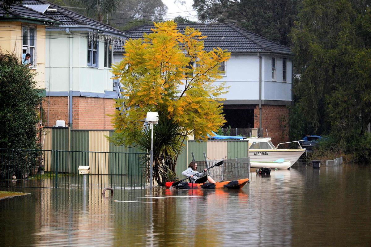 Una residente rema en un kayak para desplazarse desde su zona residencial inundada cerca del desbordado río Hawkesbury en el suburbio de Windsor, al noroeste de Sidney, el 6 de julio de 2022.