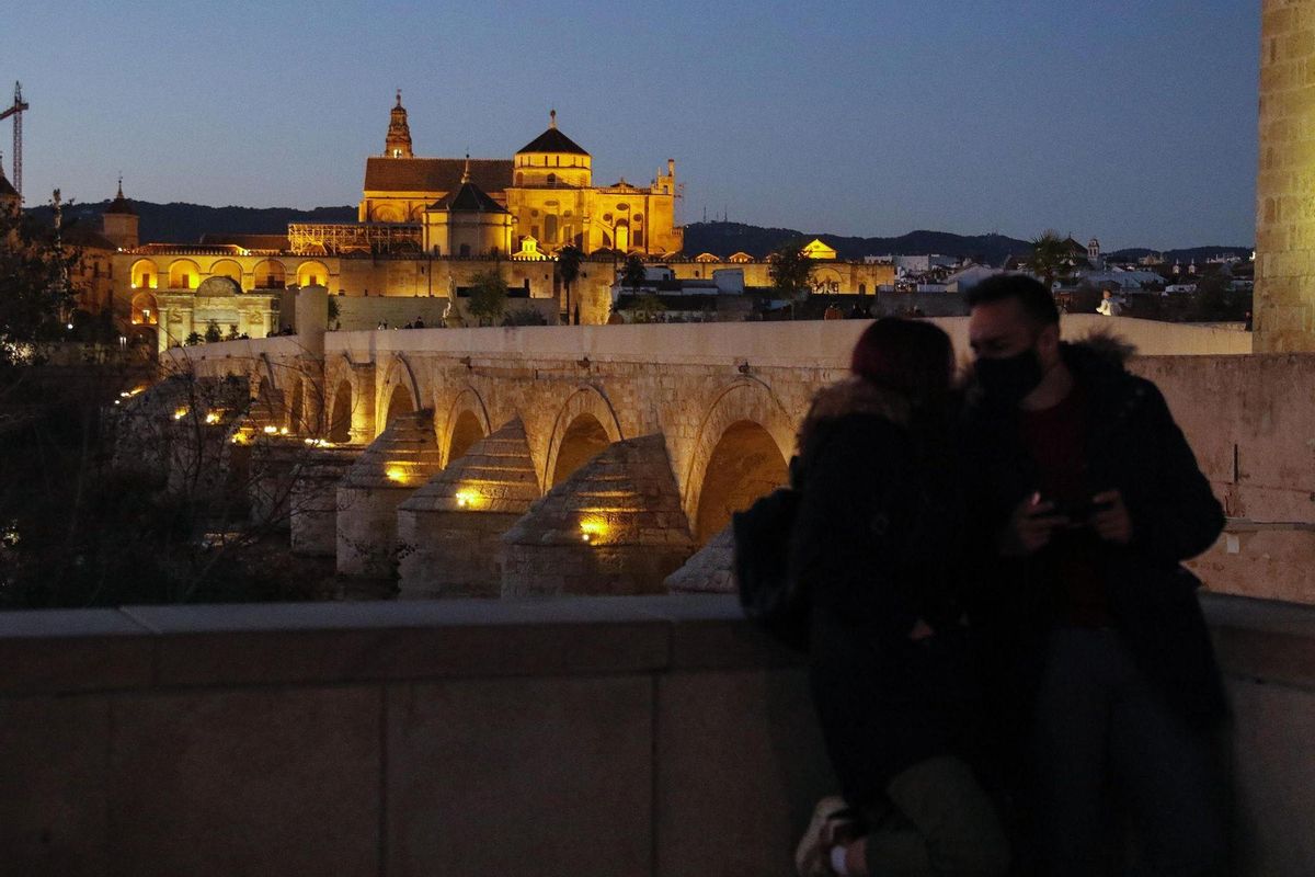 Dos personas frente al Puente Romano de Córdoba.