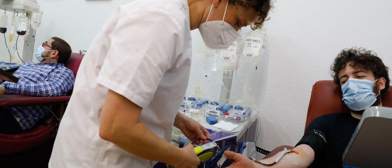 Una enfermera prepara todo lo necesario para realizar una aféresis al donante Pelayo Rodríguez, con Antonio Pérez a la izquierda. | Mara Villamuza