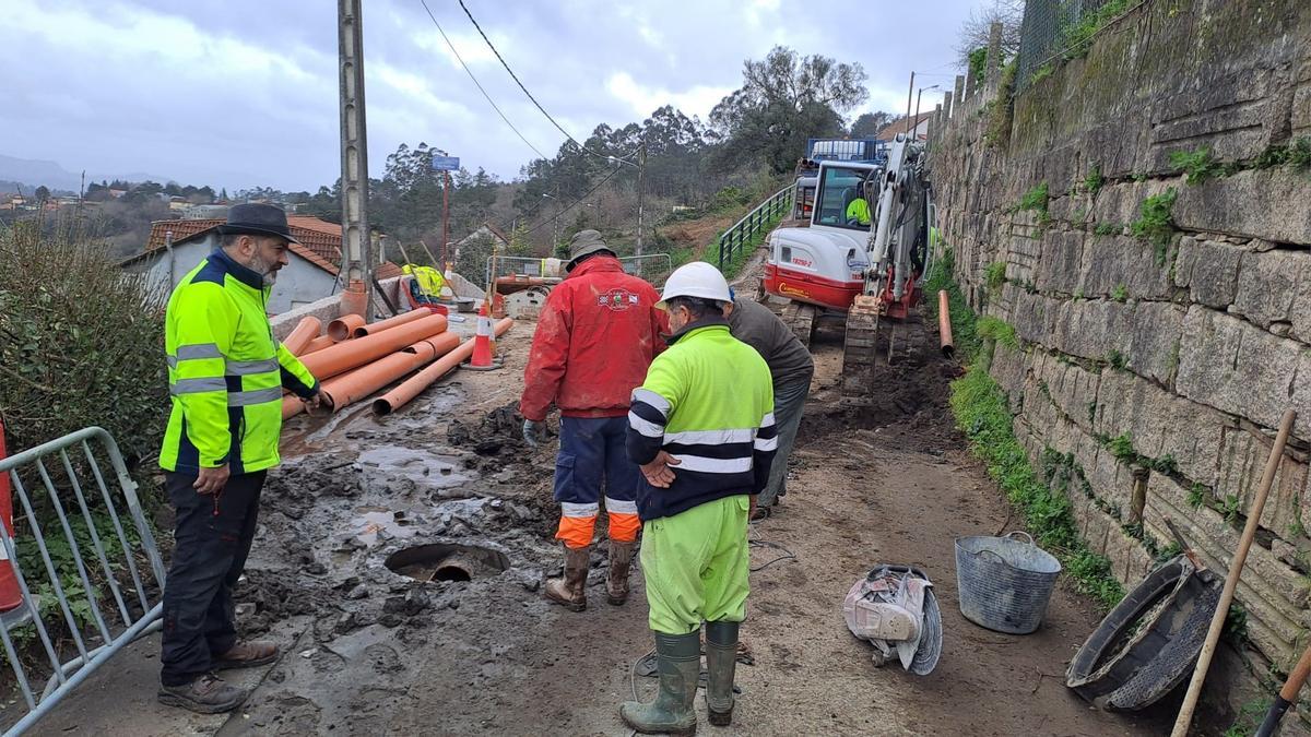 Los operarios durante los trabajos de ampliación del saneamiento de Cabeiro con el edil Robeito Villar (izq.).