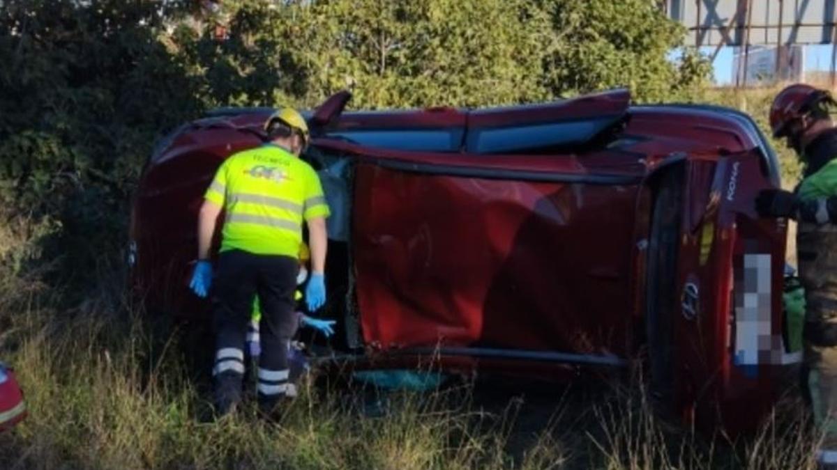 Bomberos y sanitarios, en el lugar del suceso, junto al coche volcado.
