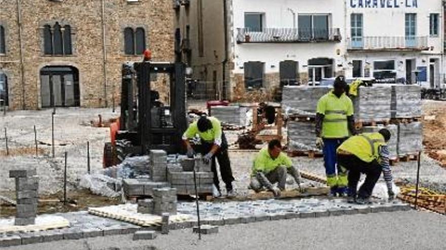 Els operaris treballant en la col·locació del nou paviment de la Platja.