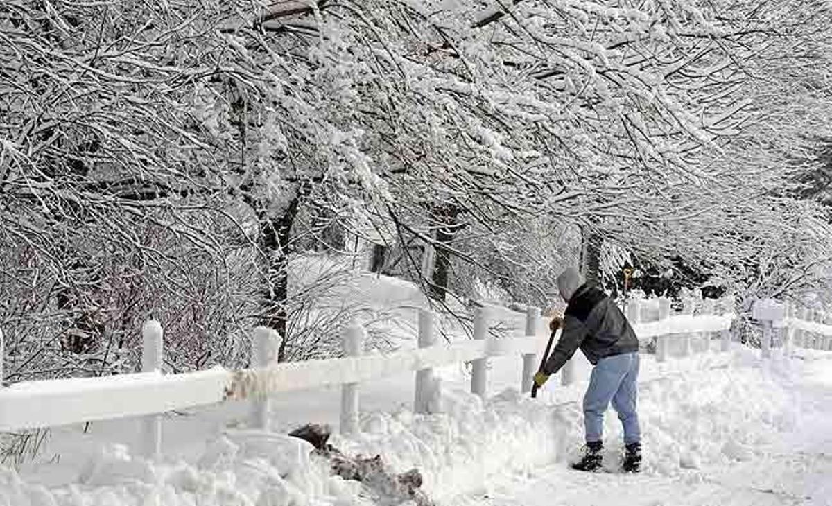 Mike Burow tracta de retirar amb una pala la neu que s’acumula a la tanca de casa seva a Slinger, Wisconsin (Estats Units).
