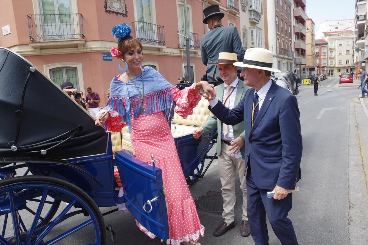 La abanderada, María Barranco, baja de la carreta con la ayuda del alcalde de Málaga, Francisco de la Torre.