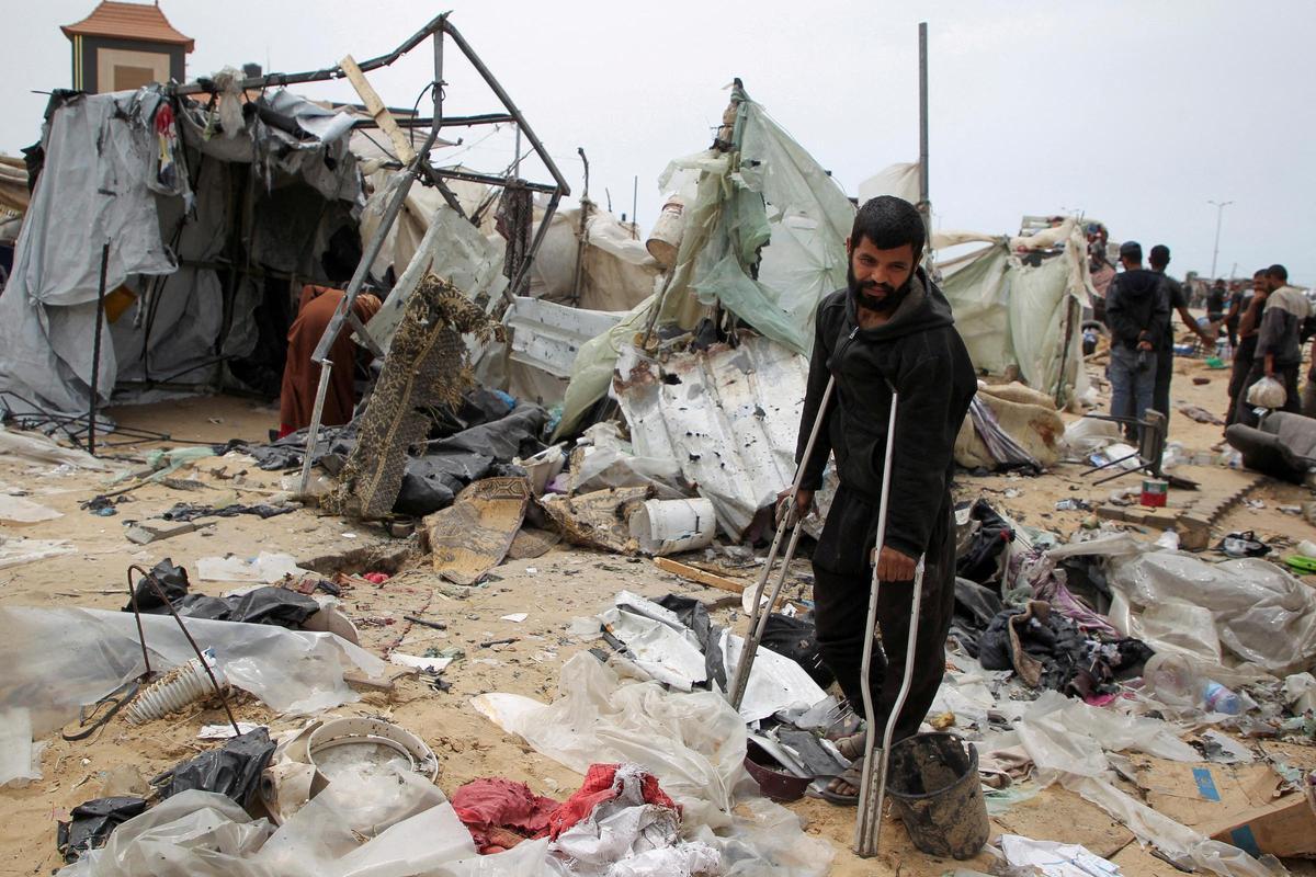 Palestinos inspeccionan un campamento de tiendas de campaña dañado en un ataque israelí durante una operación militar israelí en Rafah.