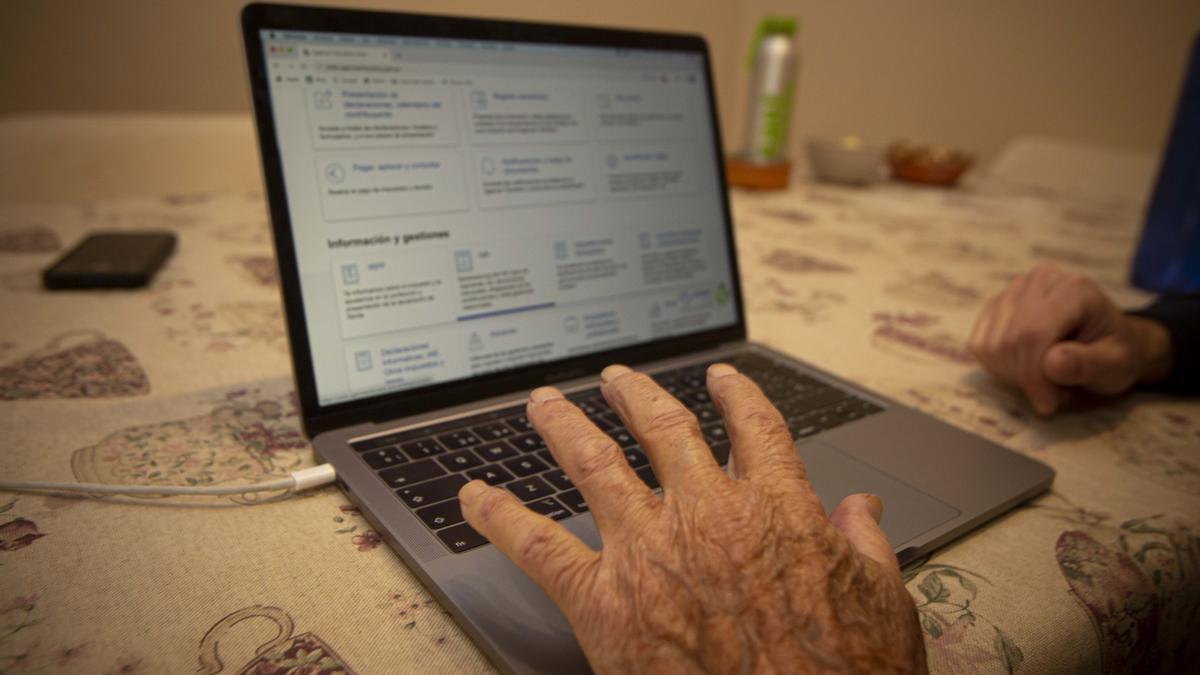Una persona mayor trata de navegar por internet en un ordenador.