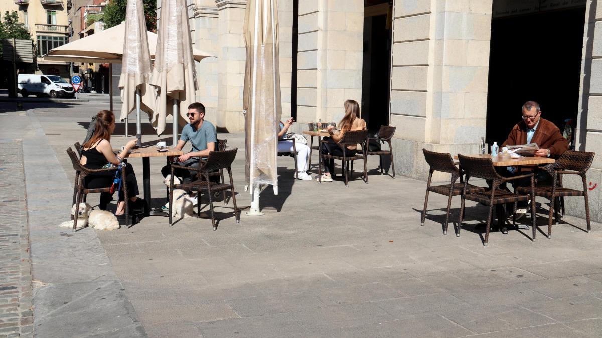 Pla obert d&#039;una de les terrasses de plaça de la Independència plenes de gent fent un cafè.