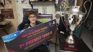 Andoni Payo, junto a su último trofeo obtenido en julio por el club de fútbol Levante Unión Deportiva, mientras muestra el cartel de ganador del FIFA19 Global Series en España.