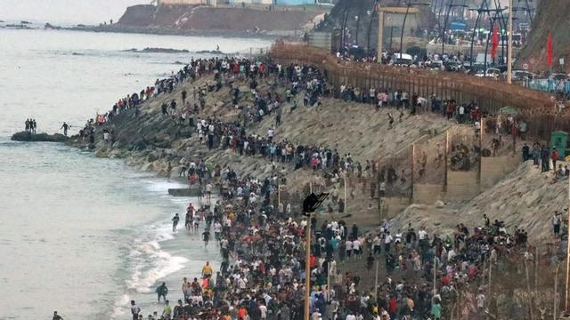Multitud de persones es concentren a la part marroquina de la platja del Tarajal per intentar accedir a Ceuta. EFE / Reduan