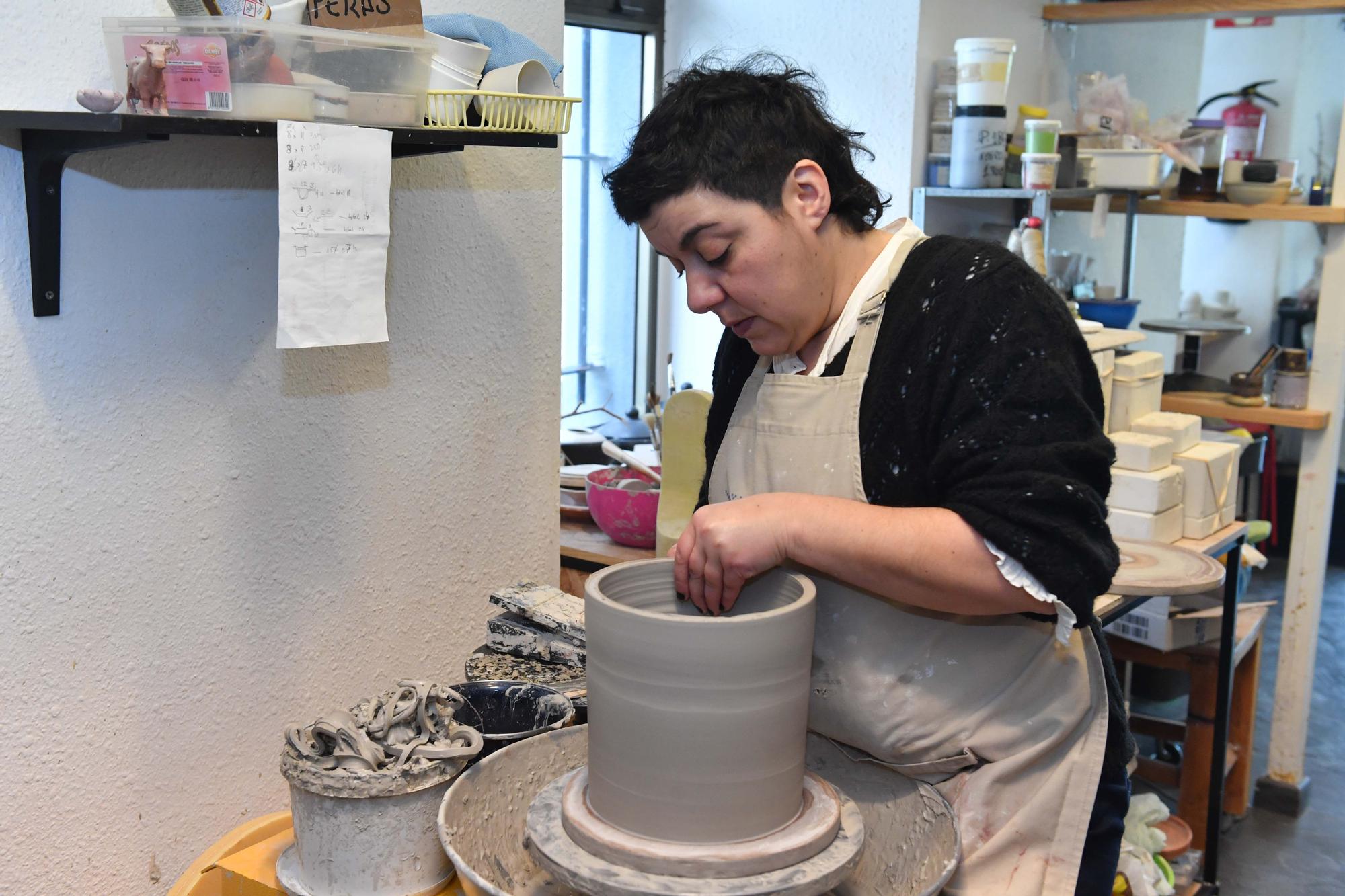 Laura Delgado con los vasos tiki ganadores, una combinación de culturas entre Polinesia y Galicia, y otras obras realizadas por esta ceramista en su taller de Cambre, en el que también da clases a pequeños grupos.